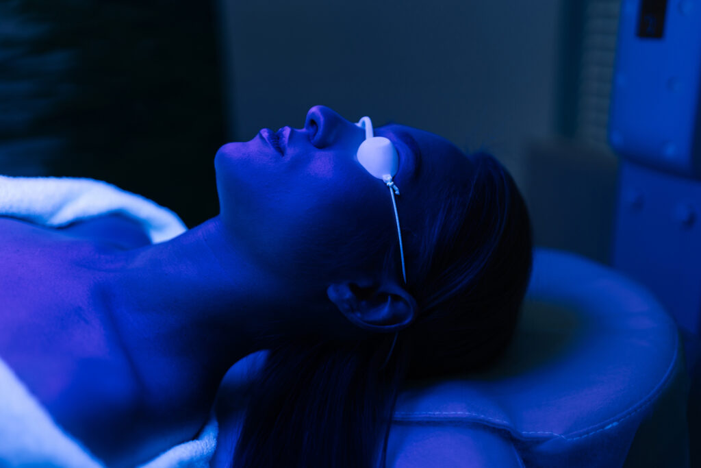 Closeup on face of a female patient as she undergoes blue LED light therapy for skin rejuvenation and acne treatment for which-wavelength-is-best-for-acne blog.